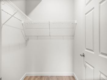 an empty closet in a home with white walls and a white closet door